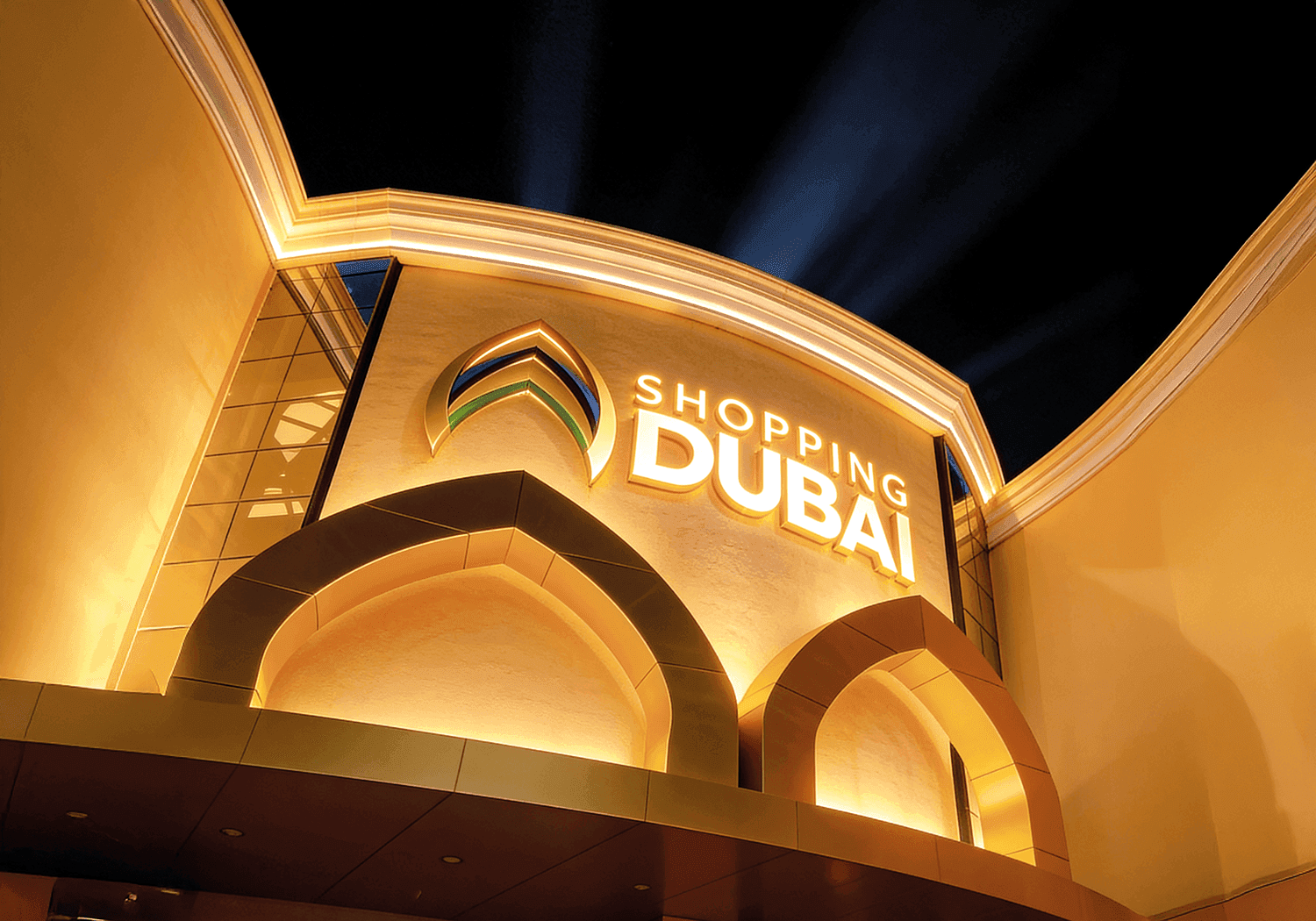 Fachada do Shopping Dubai iluminada à noite, com o letreiro do shopping em destaque
